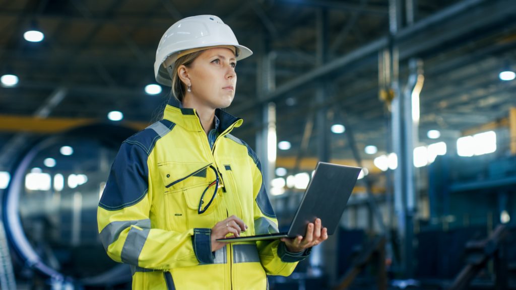 woman wearing hardhat and holding laptop